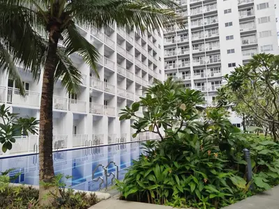 a hotel with a palm tree in front of a building at Pasay Shore Residences with one bedroom with balcony in Manila