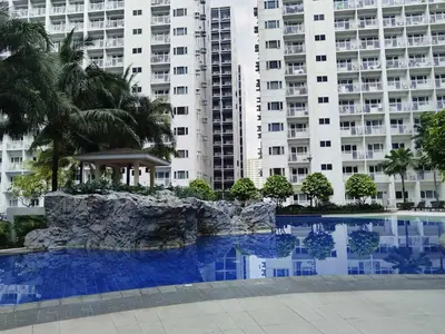 a swimming pool in front of a large building at Pasay Shore Residences with one bedroom with balcony in Manila