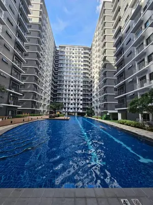 a large swimming pool in front of two large apartment buildings at Best Place For You - Mall of Asia & Airport in Manila
