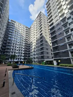 a swimming pool in front of two large buildings at Best Place For You - Mall of Asia & Airport in Manila