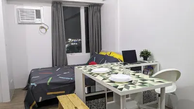 a room with a table with a laptop and a bed at Cozy Studio Suite in Muntinlupa in Manila