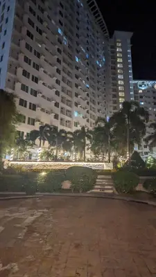a large building with palm trees in front of it at Cozy Studio Suite in Muntinlupa in Manila