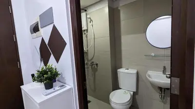 a bathroom with a toilet and a sink and a mirror at Cozy Studio Suite in Muntinlupa in Manila