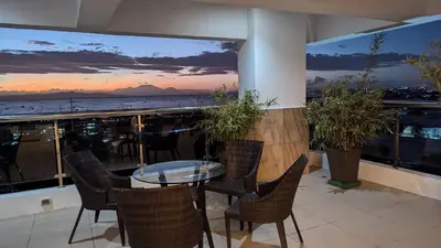 a balcony with a table and chairs and a view of the ocean at Cozy Studio Suite in Muntinlupa in Manila