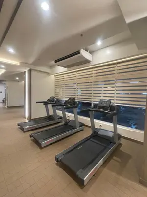 a gym with three treadmills and a swimming pool at Vincondotel Near BGC 3BR Fairlane in Manila