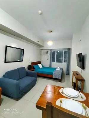 a living room with a blue couch and a bed at Sonia Suite at The Beacon Makati in Manila