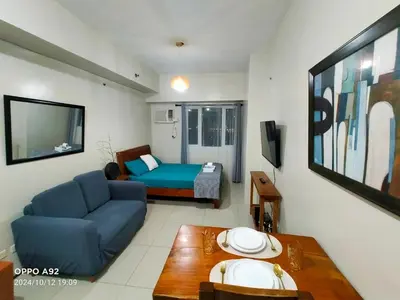 a living room with a blue couch and a bed at Sonia Suite at The Beacon Makati in Manila