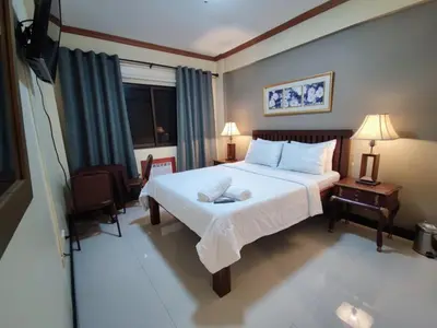 a bedroom with a large bed with white sheets at Spring Plaza Hotel in Dasmariñas