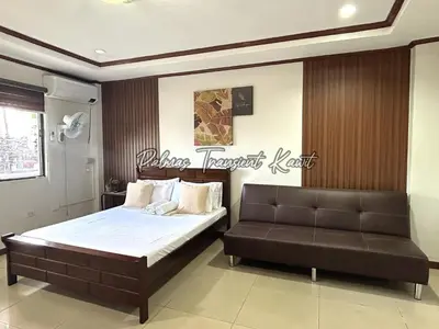 a bedroom with a bed and a leather couch at Palmas Transient Kawit in Kawit