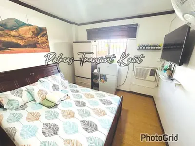 a bedroom with a bed and a kitchen with a refrigerator at Palmas Transient Kawit in Kawit