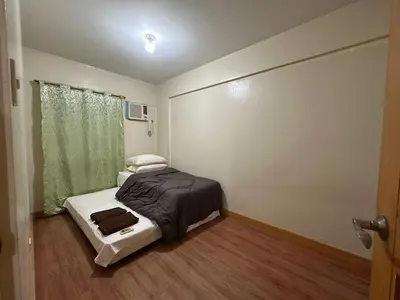 a small bedroom with a bed and a window at Homey Staycation in Taguig in Manila