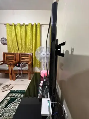 a computer monitor in a room with a yellow curtain at Homey Staycation in Taguig in Manila