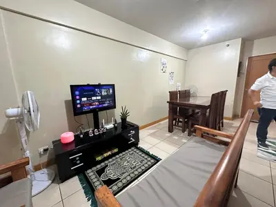 a man is standing in a living room with a table at Homey Staycation in Taguig in Manila