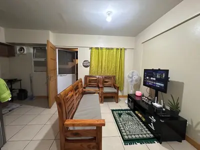 a living room with a couch and a television at Homey Staycation in Taguig in Manila