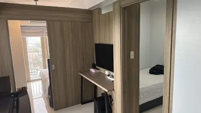 a room with a bed and a desk with a television at Condo next door in Manila