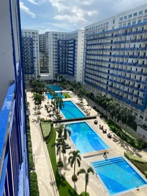 an aerial view of a resort pool with palm trees and buildings at Sea Residences MOA Pasay City - Reynil in Manila