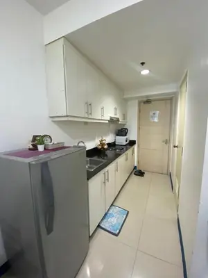 a small kitchen with white cabinets and a hallway at Sea Residences MOA Pasay City - Reynil in Manila