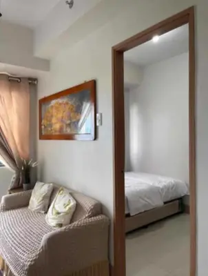 a bedroom with a bed and a chair and a mirror at JL shore Staycation in Manila