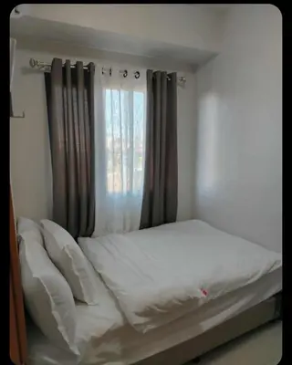 a bed in a bedroom with a window at JL shore Staycation in Manila