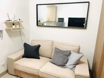 a living room with a couch and a mirror at Pasay Condo near MOA, NAIA, CBD and Casinos in Manila