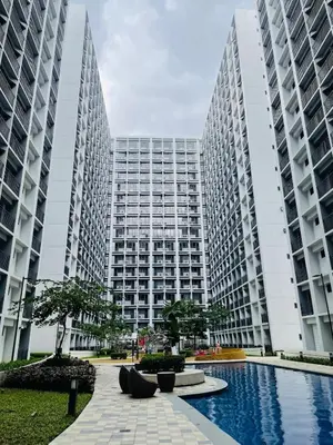 two tall buildings with a pool in front of them at Pasay Condo near MOA, NAIA, CBD and Casinos in Manila