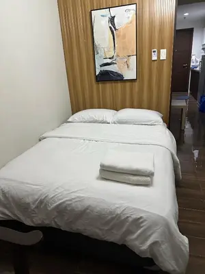 a bed with two white pillows and a picture on the wall at Affordable Ayala Makati 1BR Condo in Manila