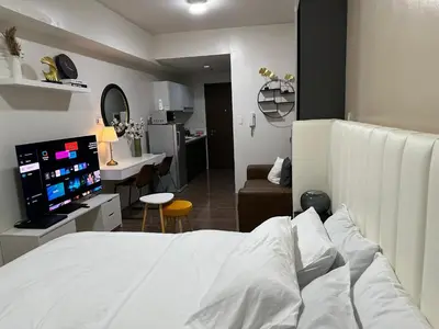 a bedroom with a white bed and a kitchen at King-size Bed Makati Condo in Manila