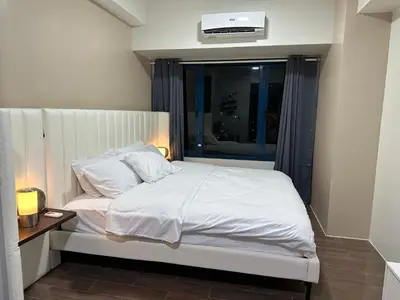 a bedroom with a white bed with a window at King-size Bed Makati Condo in Manila
