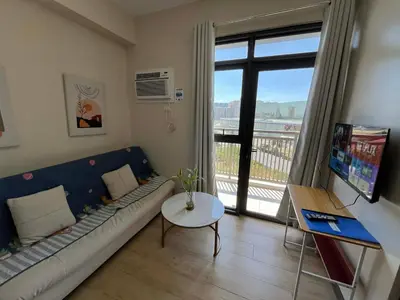 a living room with a couch and a table and a window at Gentry Manor Family Suite Facing Okada Fountain WiFi Netflix Near Airport 8A in Manila