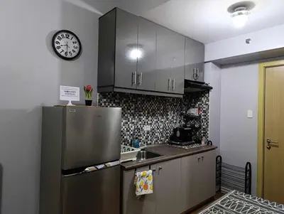 a kitchen with a refrigerator and a clock on the wall at Kaths Place in Manila