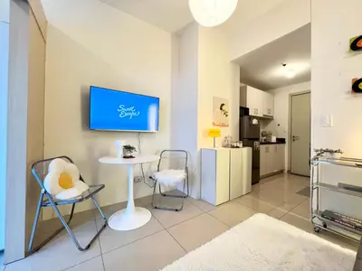 a living room with a table and chairs and a kitchen at Fun Pop-Art Inspired Makati Studio in Manila