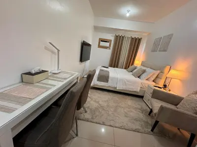 a bedroom with a bed and a desk with chairs at Green 2 SMDC - STUDIO TYPE Condo - Gems Suite Staycation in Dasmariñas