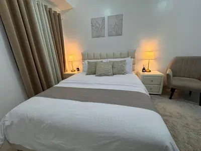 a bedroom with a large white bed and a chair at Green 2 SMDC - STUDIO TYPE Condo - Gems Suite Staycation in Dasmariñas