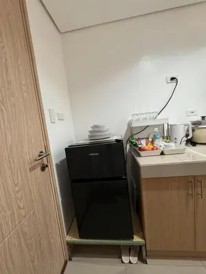 a small kitchen with a black refrigerator and a counter at Green 2 SMDC - STUDIO TYPE Condo - Gems Suite Staycation in Dasmariñas