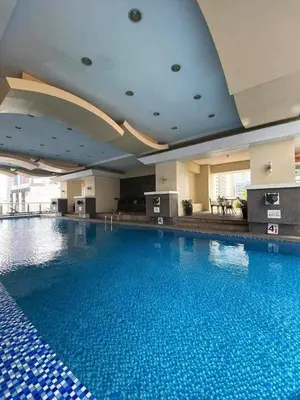 a large swimming pool with blue water in a hotel at Birch Tower Malate Accommodation by T&T in Manila