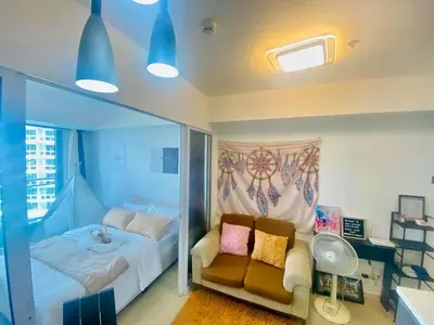 a bedroom with a bed and a couch and a window at Sole Sister Azure Staycation in Manila