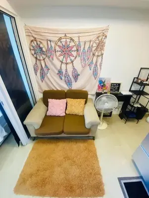a living room with a brown couch with two pillows at Sole Sister Azure Staycation in Manila