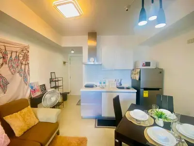 a living room with a couch and a table and a kitchen at Sole Sister Azure Staycation in Manila