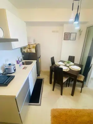 a kitchen and dining room with a small table and chairs at Sole Sister Azure Staycation in Manila