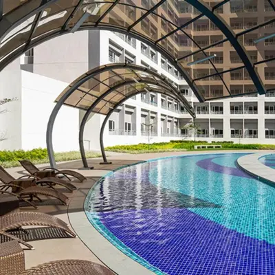 an indoor swimming pool with chairs and a building at Cozy Stay Near BGC & Airport in Manila