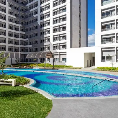 a swimming pool in front of a building at Cozy Stay Near BGC & Airport in Manila