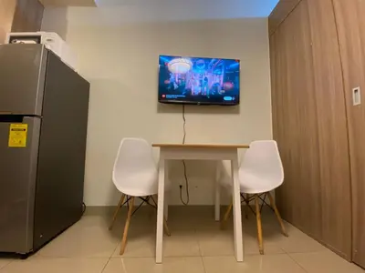 a kitchen with a table and a tv on the wall at La Casa de Maria in Manila