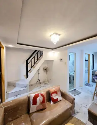 a living room with a brown couch and stairs at Tiny home in Naic in Naic