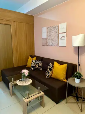 a living room with a black couch and yellow pillows at Relax and Unwind A Homey Escape Near MOA and NAIA in Manila