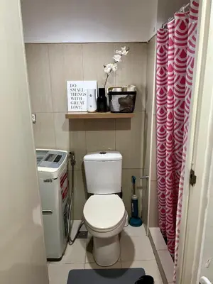 a small bathroom with a toilet and a pink shower curtain at Relax and Unwind A Homey Escape Near MOA and NAIA in Manila