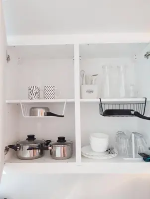 a white cabinet with pots and pans and dishes at Relax and Unwind A Homey Escape Near MOA and NAIA in Manila