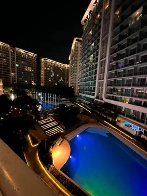 a view of a building with a swimming pool at night at Staycation In Azure Parañaque in Manila