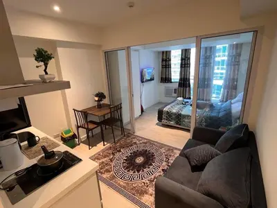 a living room with a couch and a view of a bedroom at Staycation In Azure Parañaque in Manila