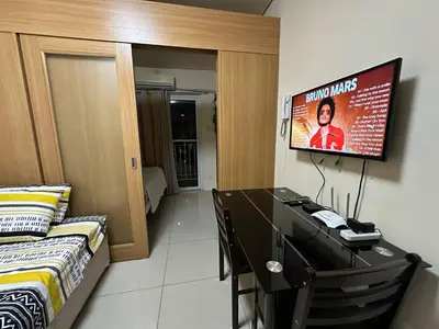 a bedroom with a desk and a tv on the wall at Macc staycation in Manila