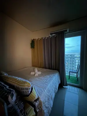 a bedroom with a bed and a window with a chair at Macc staycation in Manila